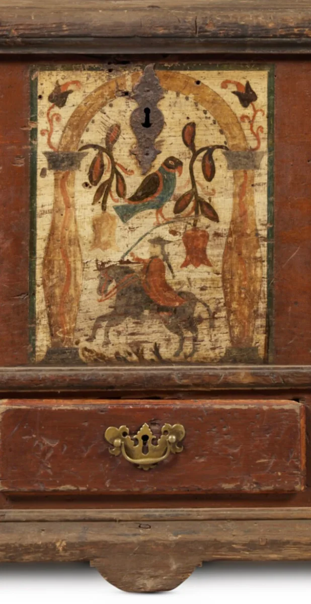 Detail of a Pennsylvania German painted chest showing a horse-and-rider scene, tulips, birds, and aged original surface
