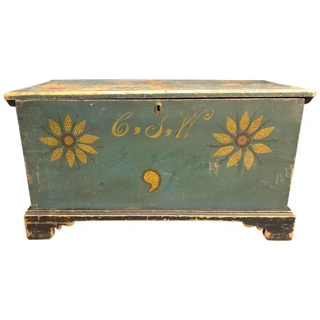 Teal-painted chest with yellow sunflower motifs and visible initials C.S.W., isolated on a white background