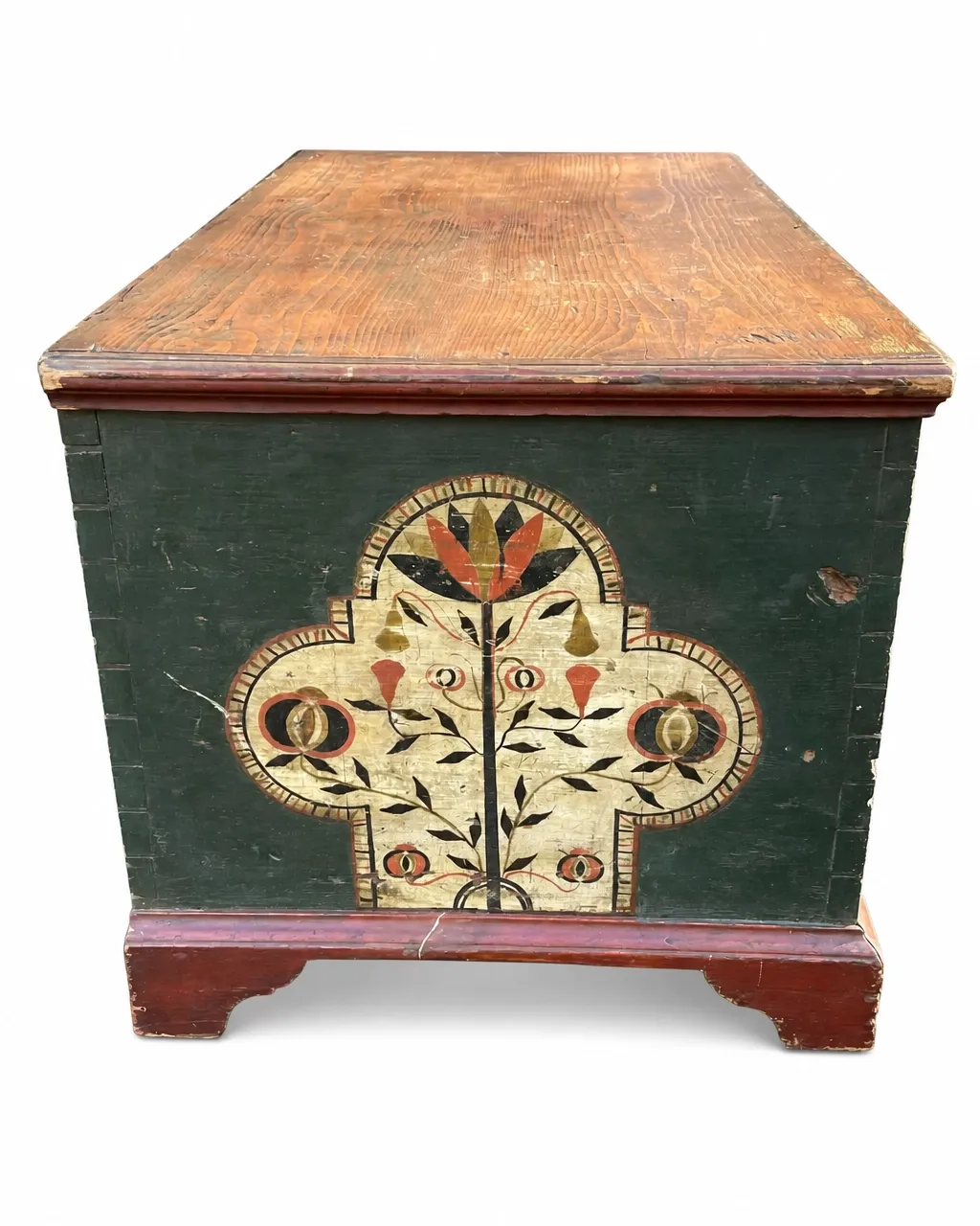 Tole-painted wooden blanket chest with dark green paint, a natural wood lid, floral decoration, and distressed red bracket feet isolated on a white background